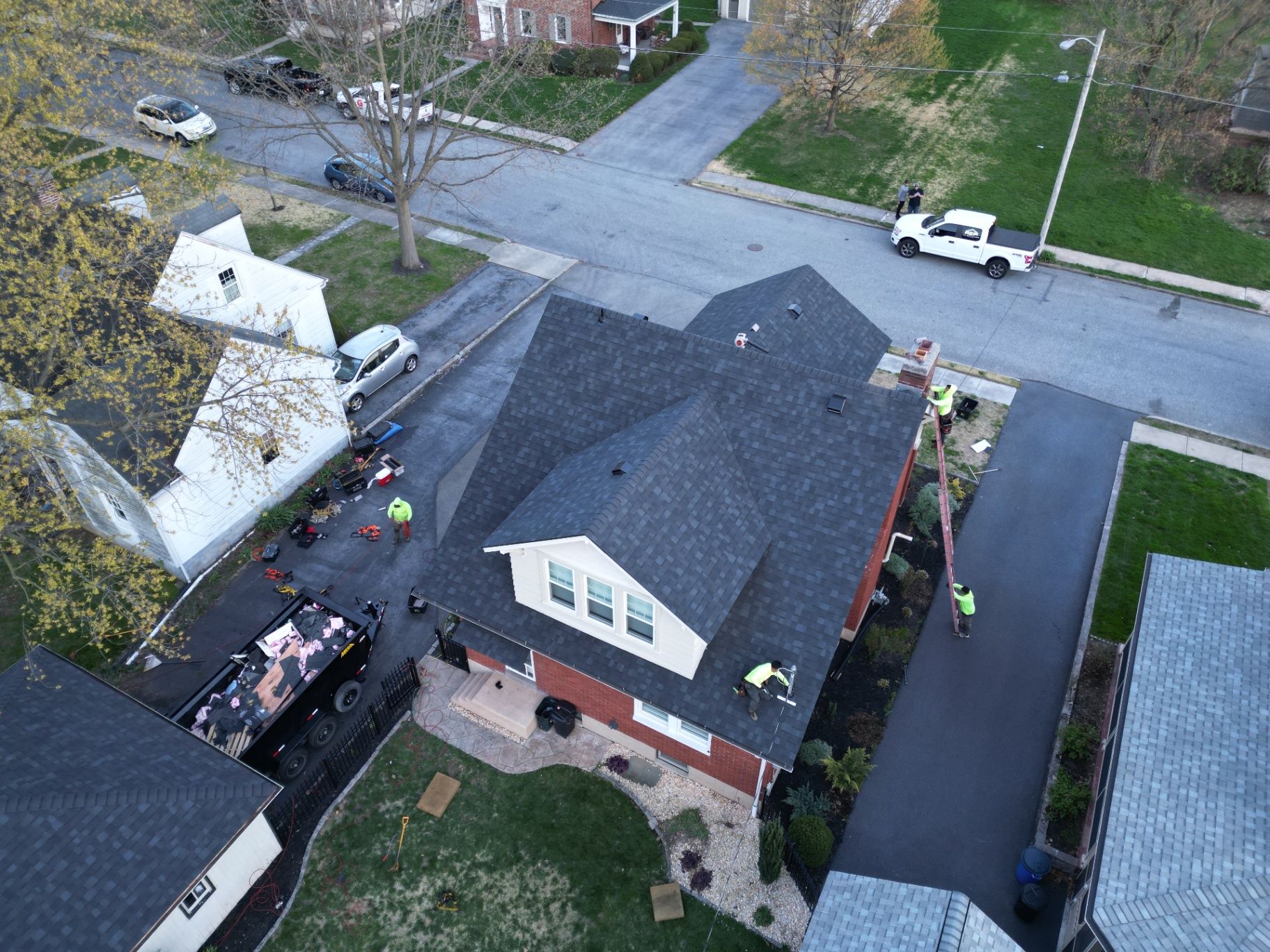 Aerial view of the completed dark shingle roof installed by REP on a brick home