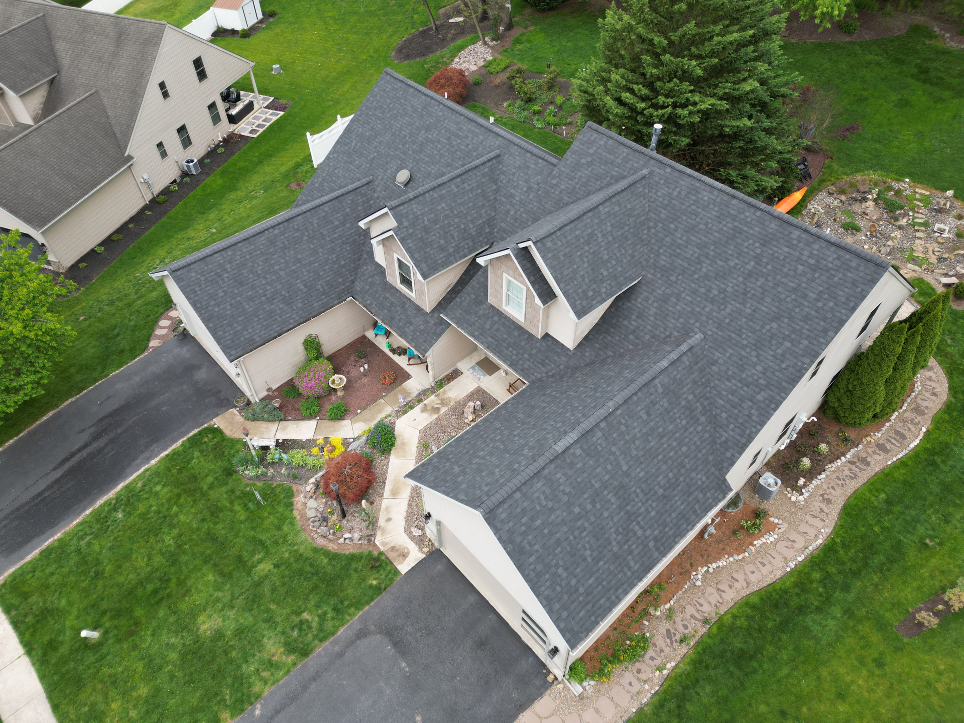 Aerial view of the completed dark charcoal architectural shingle roof installed by REP on a suburban home with dormers